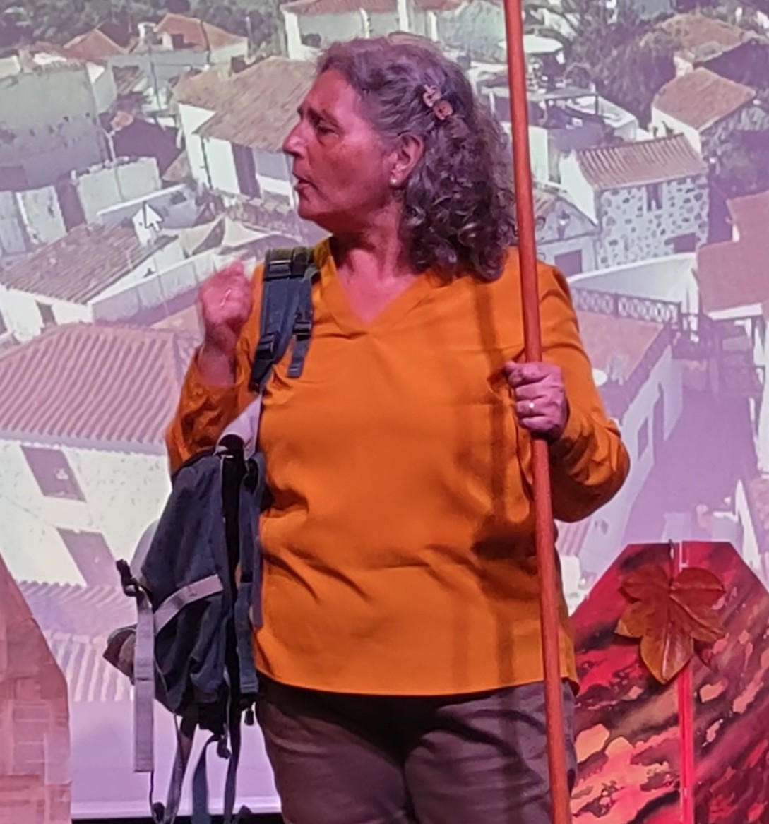 Antonia Martin, actriz, con blusa naranja y bast&oacute;n frente a fondo de pueblo